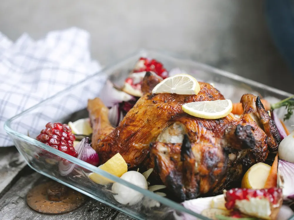 A roast chicken with vegetables, still in the dish it came out of the oven in.