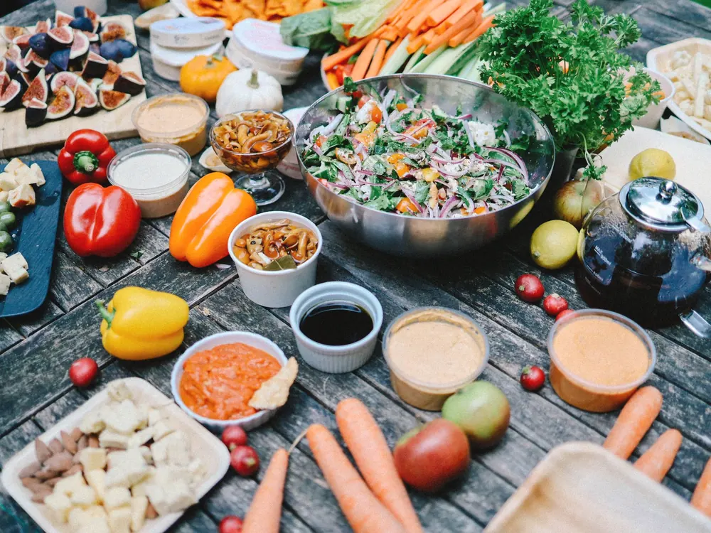 A wooden table covered with vegetables, salads and small bowls of dips.